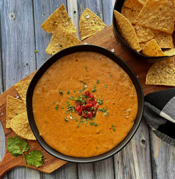 overhead view - black bowl with chili's queso dip garnished with cilantro and minced tomato