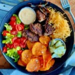 overhead view - black bowl with burger bowls with lettuce, tomato, shredded cheese, sweet potato fries and burger sauce.