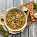 overhead view - bowl of chicken pastina soup with breadsticks and butter