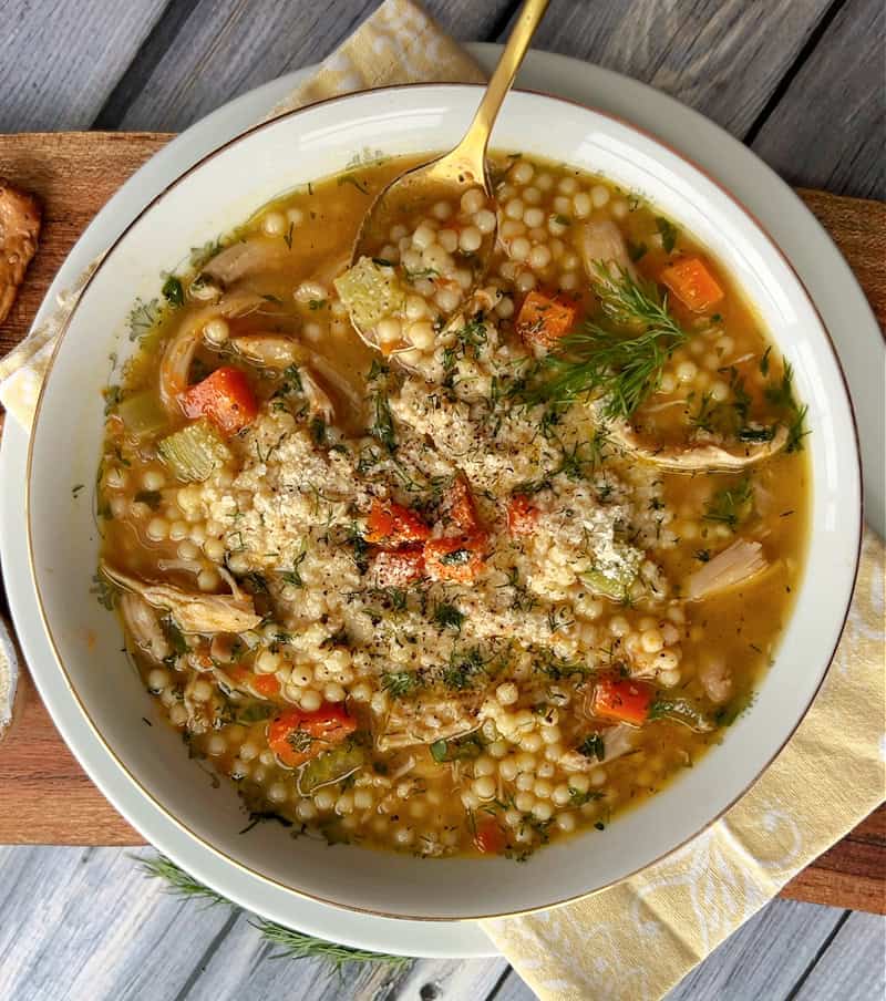 overhead view chicken pastina soup with spoon scooping out some