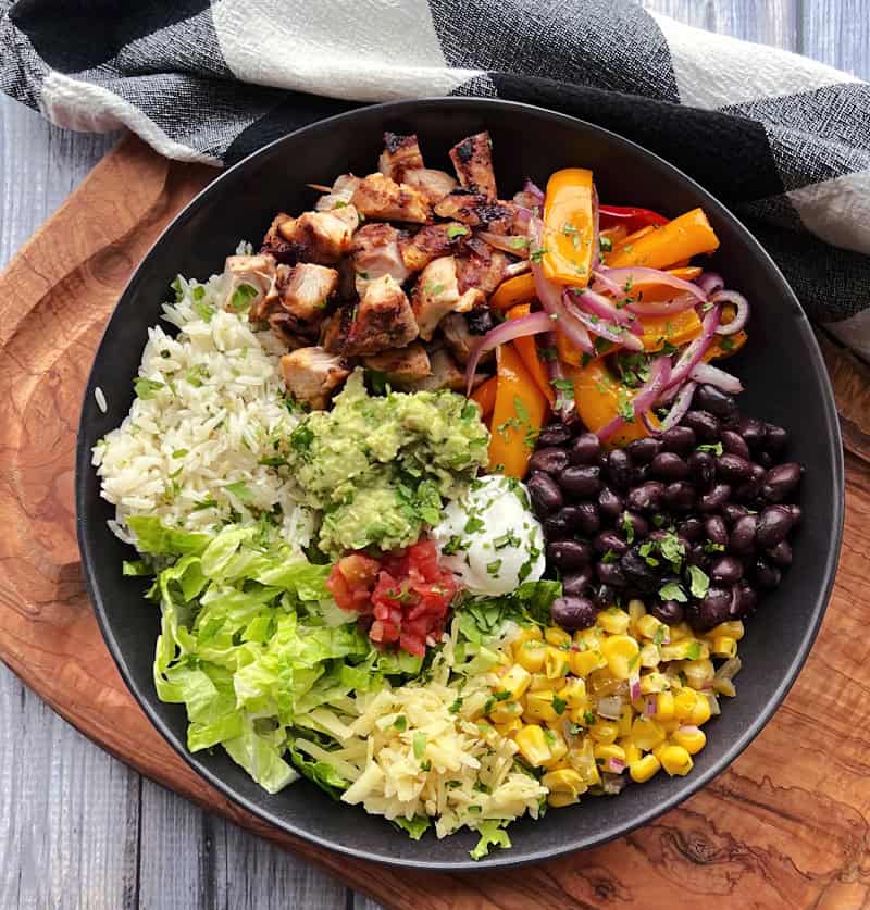 chicken burrito bowl in black bowl with checked napkin next to it