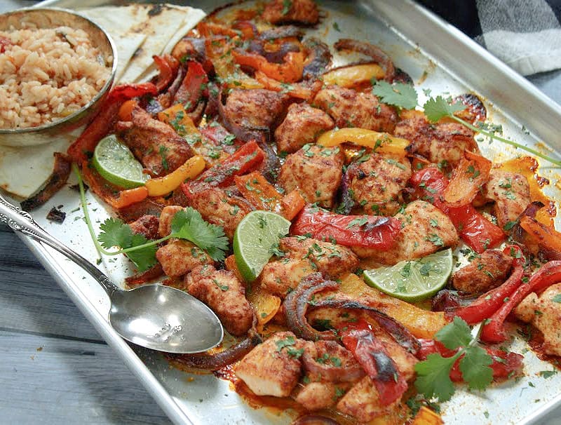 overhead view sheet pan chicken and fajitas garnished with lime slices