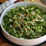 white bowl with kale crunch salad topped with toasted almonds