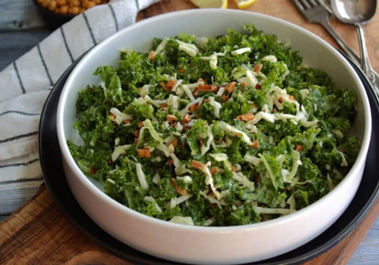 white bowl with kale crunch salad topped with toasted almonds