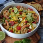 overhead view white bowl with corn salad garnished with lime slices and fresh basil