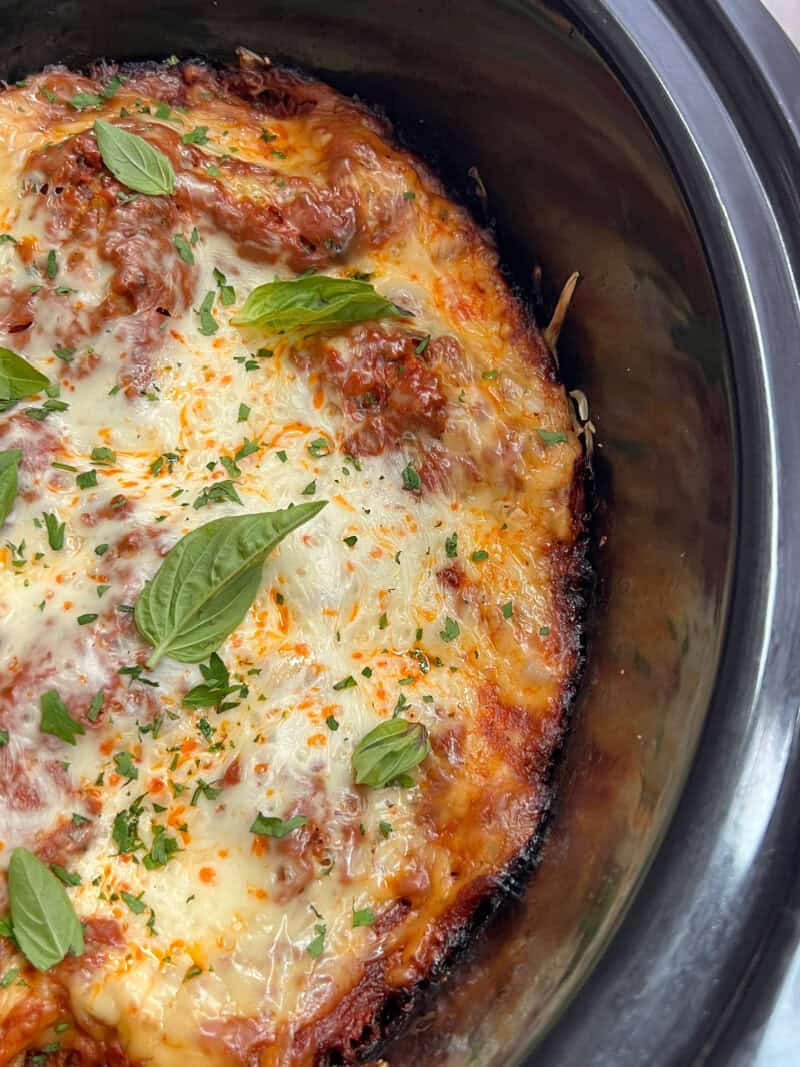 overhead view of slow cooker lasagna in the crockpot garnished with basil leaves
