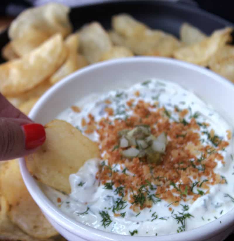 white bowl with dill pickle ranch dip and potato chip scooping into it.