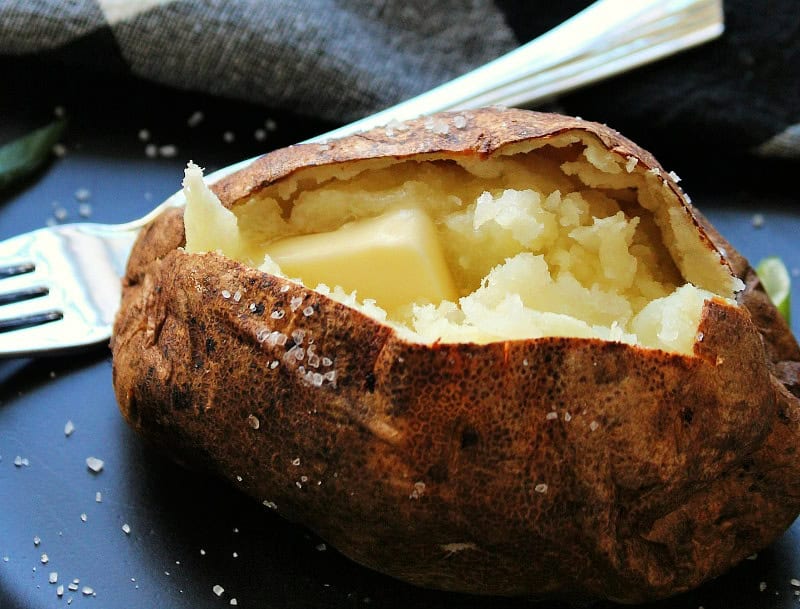 black plate with air fryer baked potatoes with butter and salt