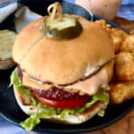 cheeseburger with burger sauce running down the side of it and tater tots on the side.