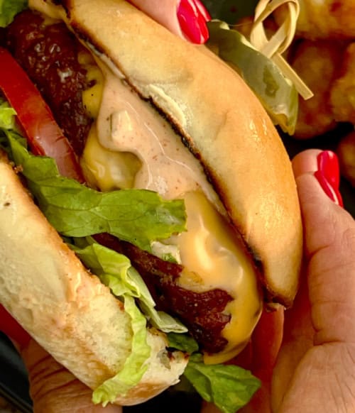 Delicious cheeseburger featuring melted cheese, fresh lettuce, tomato, and a beef patty in a toasted.