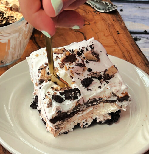 slice of chocolate lasagna on a white plate with fork digging into it
