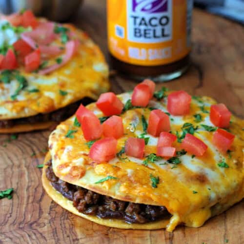 whole mexican pizza with taco bell taco sauce in the background on wood board