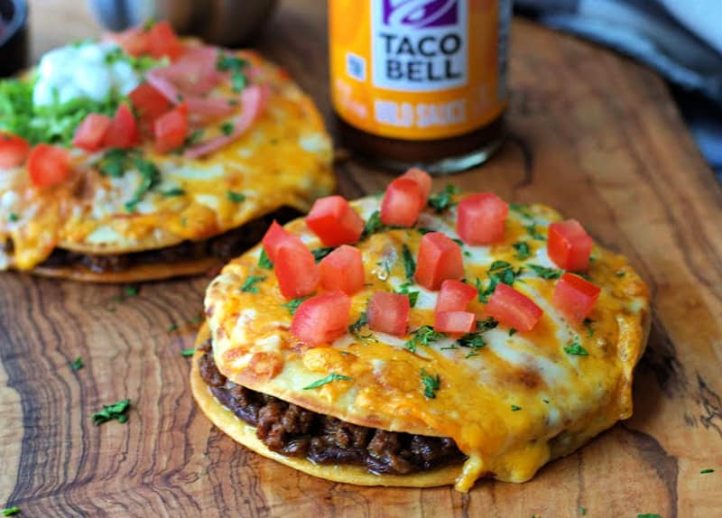 whole mexican pizza with taco bell taco sauce in the background on wood board