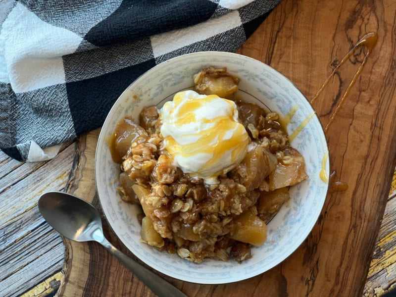 overhead view white bowl with apple crisp and a scoop of vanilla ice cream