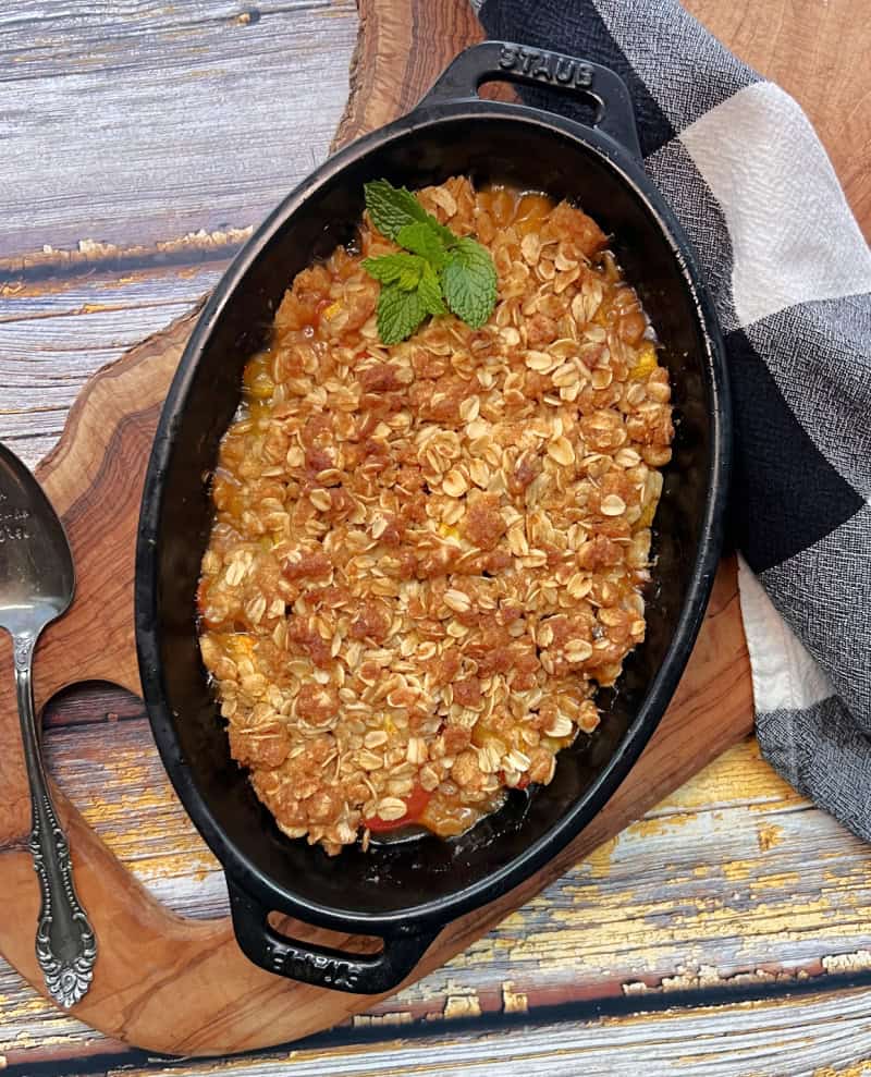 black baking dish with peach crisp just out of the oven and golden brown