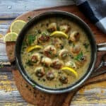 overhead view skillet with chicken piccata meatballs garnished with lemonslices