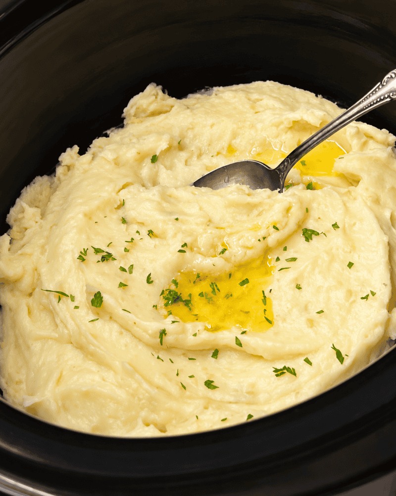 crockpot containing slow cooker mashed potatoes with pat of melted butter