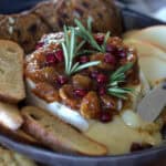 air fryer baked brie on a plate with apples, crostini and crackers