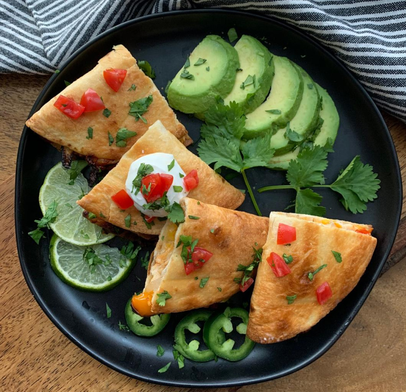 black plate with air fryer quesadillas and sliced avocado