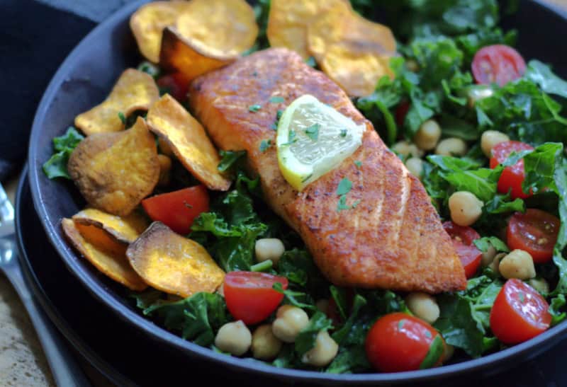 black plate with air fryer salmon and mixed green salad