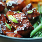 closeup air fryer teriyaki salmon bites garnished with sesame seeds and green onions