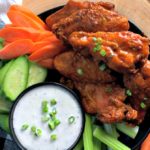 black plate piled with air fryer chicken wings with buffalo sauce