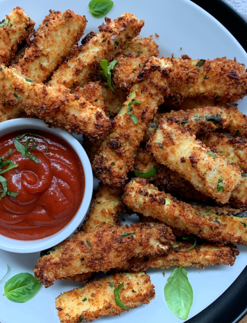 white plate with air fryer zucchini fries and side of marinara for dipping