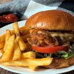 breaded chicken sandwich on a bun with french fries
