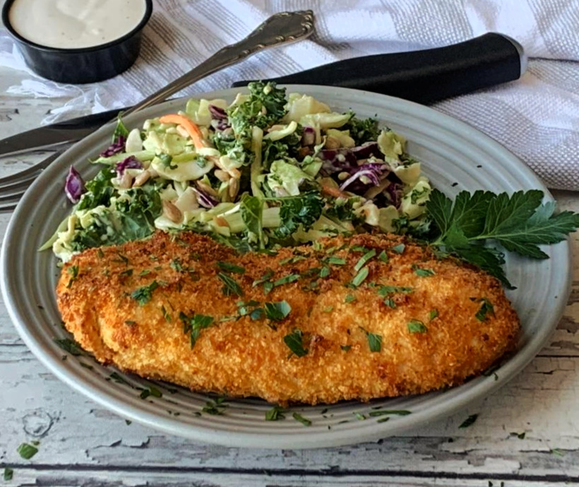 gray plate with sliced air fryer parmesan crusted chicken and side salad