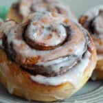 closeup of air fryer pillsbury cinnamon rolls with icing on gray plate