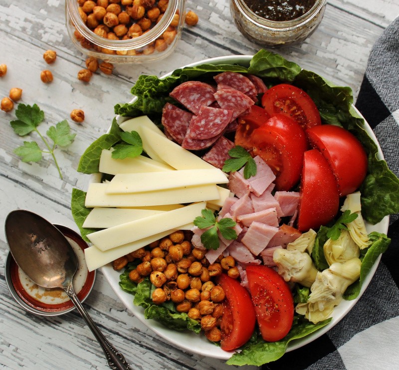 overhead view antipasto salad in bowl with jar of dressing