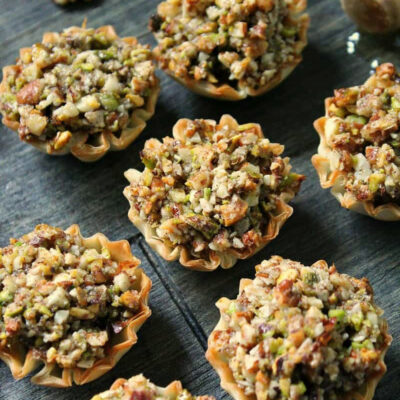 mini baklava cups on wood board drizzled with honey