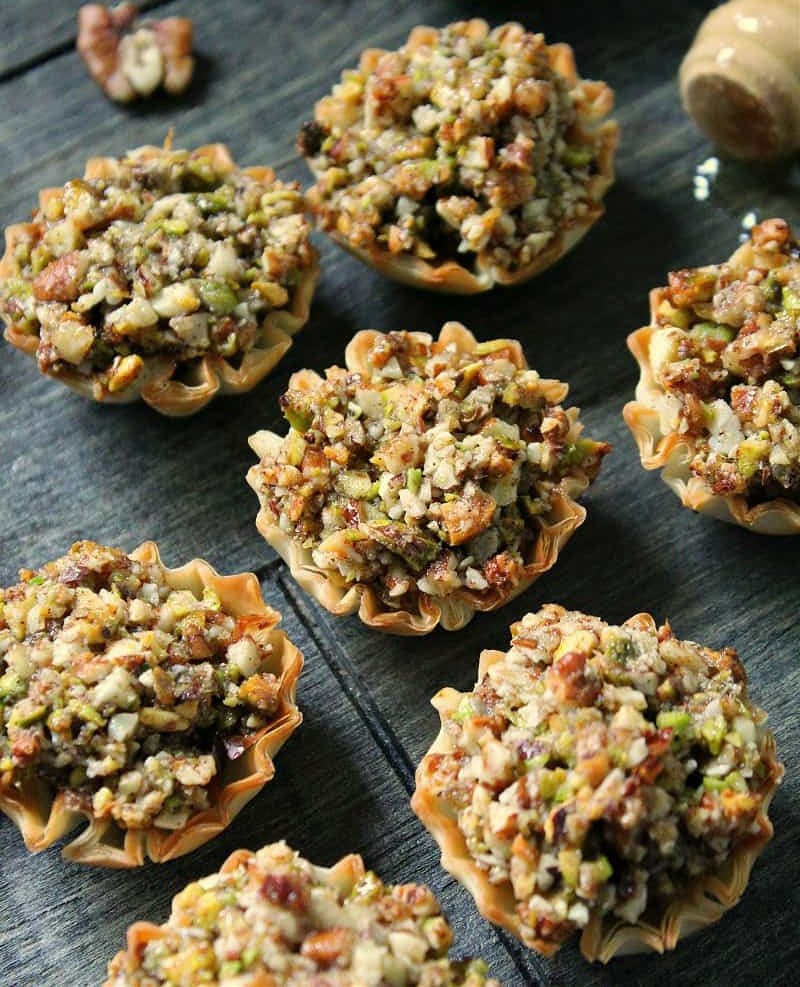 mini baklava cups on wood board drizzled with honey