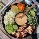 overhead view - black plate with bang bang chicken skewers, white rice and fresh chopped vegetables