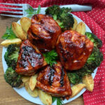 overhead view white plate with grilled split chicken breasts brushed with bbq sauce