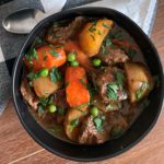 overhead view of beef stew in black bowl garnished with parsley