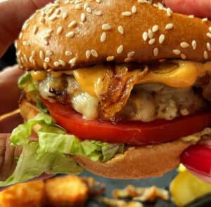 closeup of best grilled chicken burger with caramelized onions, melty cheese and chipotle mayo