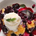 easy blueberry nectarine cobbler - overhead view of single serving in white bowl topped with vanilla ice cream