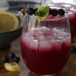 side view of blueberry vodka lemonade garnished with lemon slice and blueberries