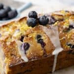 loaf of lemon blueberry zucchini bread with small bowl of blueberries in the background