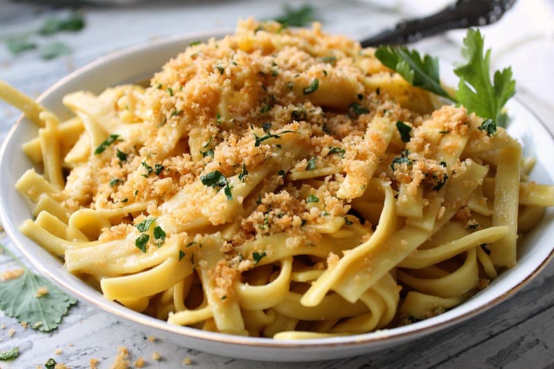 bowl of buttered noodles sprinkled with cracker crumb topping