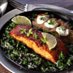 Boubon Glazed Salmon on a bed of kale garnished with lime wedge and green onions