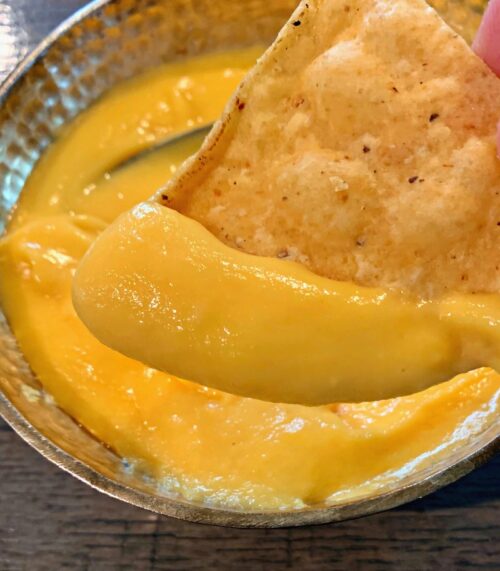 bowl of easy cheese sauce and tortilla chip scooping some out