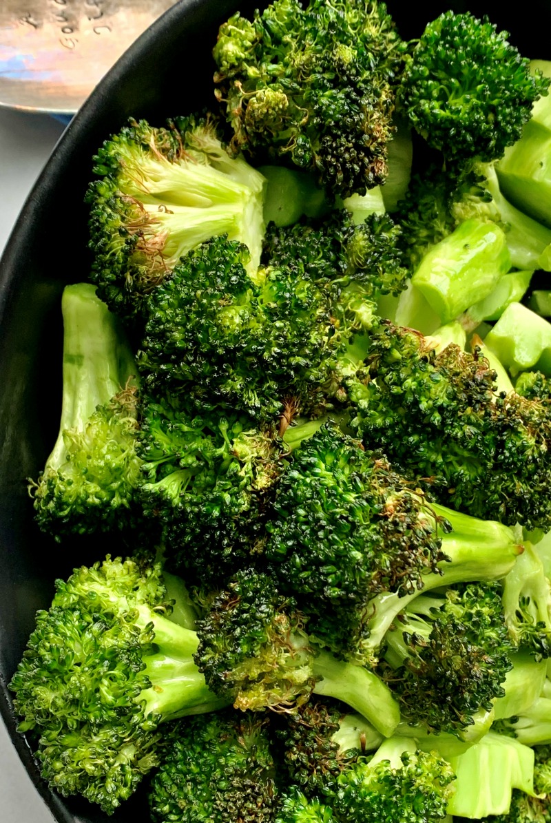 Bright green air fryer roasted broccoli in black bowl