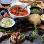 bruschetta bar on large board with variety of cheeses, meats and crostini