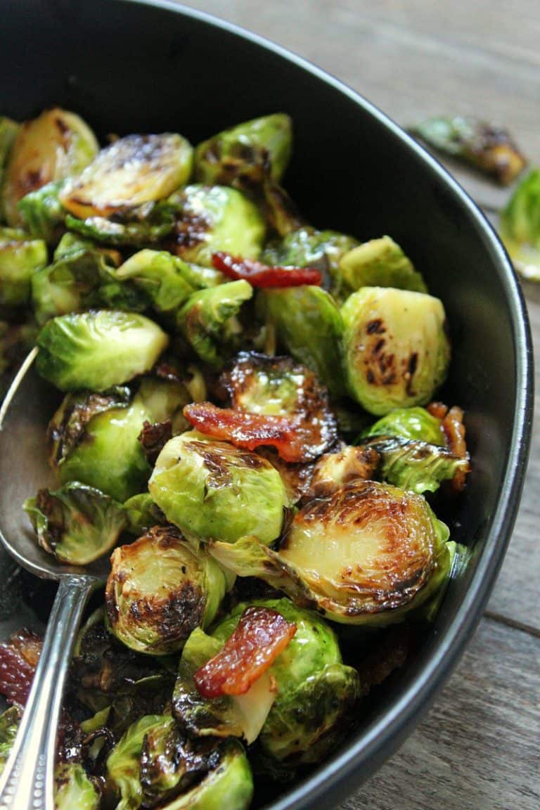 black bowl with maple bacon brussels sprouts garnished with bacon