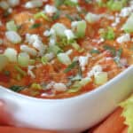 white baking dish with healthy buffalo chicken dip garnished with green onions