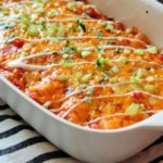 white casserole dish with buffalo chicken enchiladas made with slow cooker shredded buffalo chicken