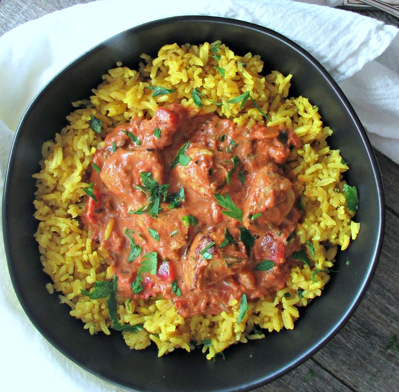 butter chicken recipe ~ overhead photo of yellow tumeric indian style rice topped with creamy butter chicken. serve with any rice or naan bread