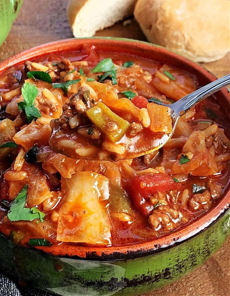 green bowl with stuffed cabbage soup and spoon scooping some out